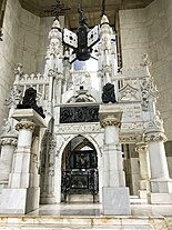 A large white, black, and gold tomb elaborately adorned with sculpture and writing, claiming to be the resting place of Cristobal Colon